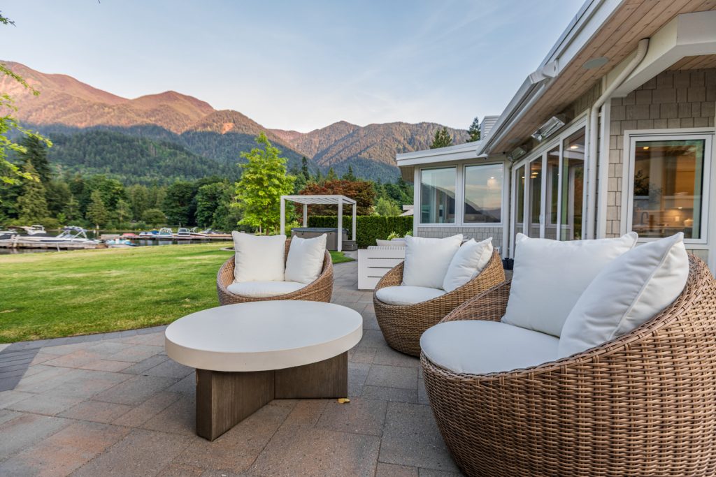 Outdoor seating area in Cultus Lake, BC with a landscaped patio, greenery, and lake views.
