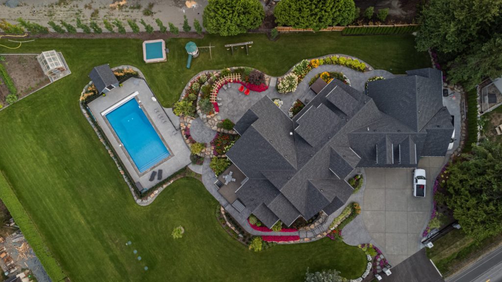 Photo of completed landscape project with pool, boulder walls, vibrant planting, concrete, paver patios and arbours.
