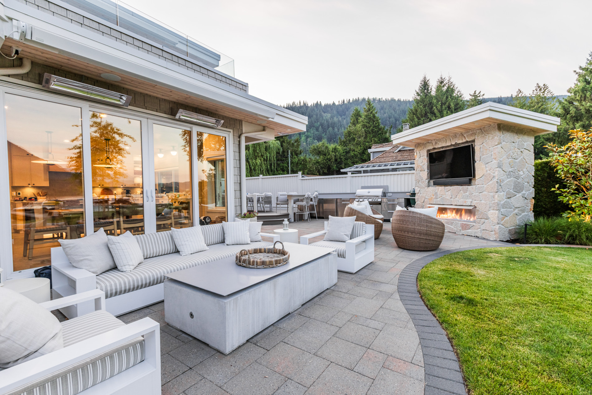 Jovak Landscape & Design lakeside home project showing pavers, outdoor kitchen and fireplace.